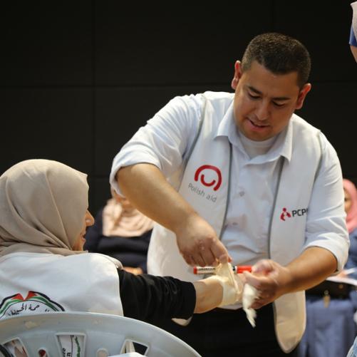 mężczyzna w kamizelce z logo Polskiej pomocy opatruje kobietę