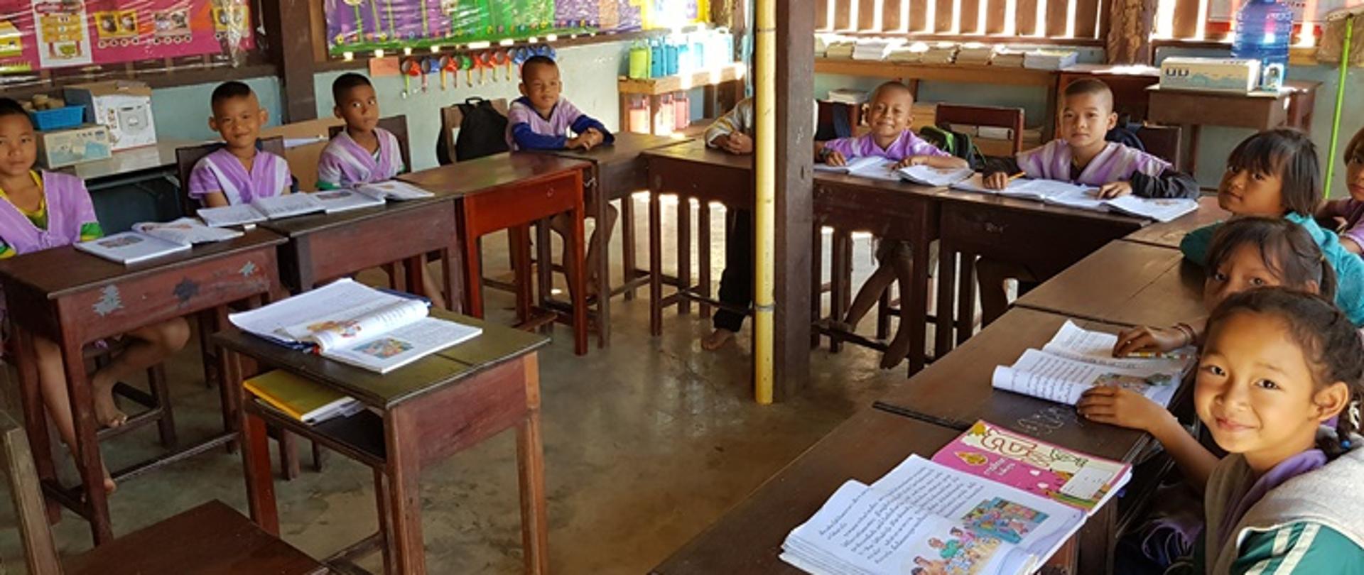 Dzieci siedzące w ławkach szkolnych z podręcznikami