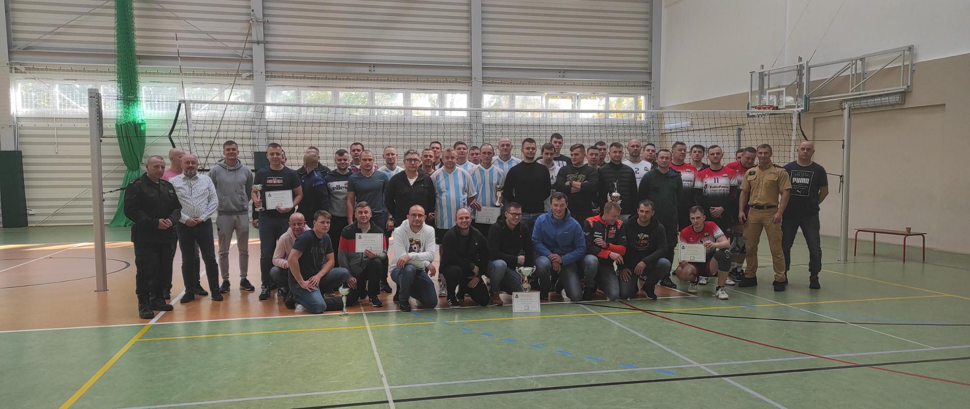 Zdjęcie zrobione na hali sportowej. Kilkudziesięciu zawodników pozuje do zdjęcia.