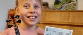 Twarz dziewczynki trzymającej skrzypce i doplom.