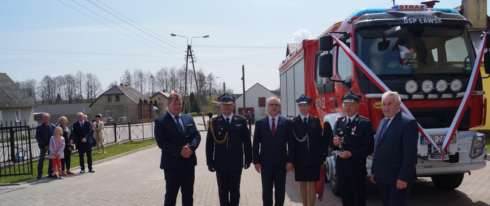 Na tle samochodu strażackiego stoją strażacy OSP, poseł na |Sejm Kazimierz Gwiazdowski, starosta powiatu grajewskiego Waldemar Remfeld, Zastępca Podlaskiego Komendanta Wojewódzkiego PSP bryg. Marcin Bielakowicz.