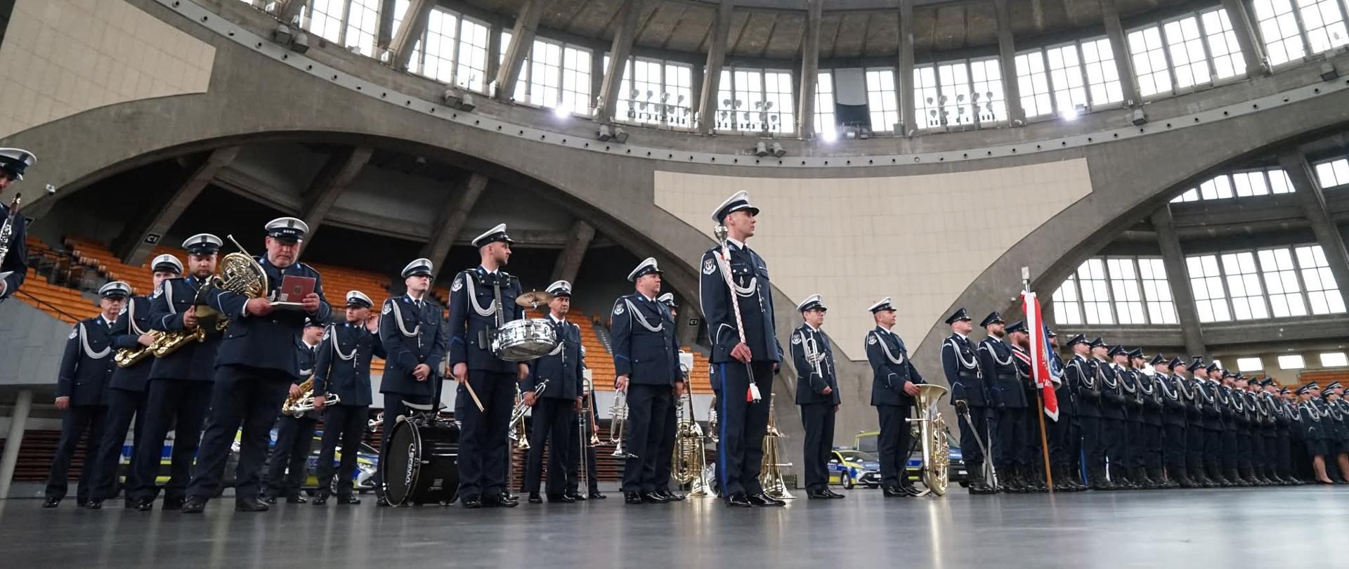 Na pierwszym planie orkiestra policyjna, na drugim planie szpaler policjantów na płycie głównej Hali Stulecia podczas uroczystości Święta Policji. 