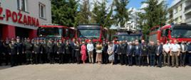 Strażacy oraz zaproszeni goście stoją na placu Komendy przed samochodami strażackimi