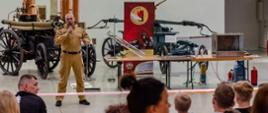 Strażak stojący na scenie i przemawiający do zgromadzonych, stojących przed nim widzów