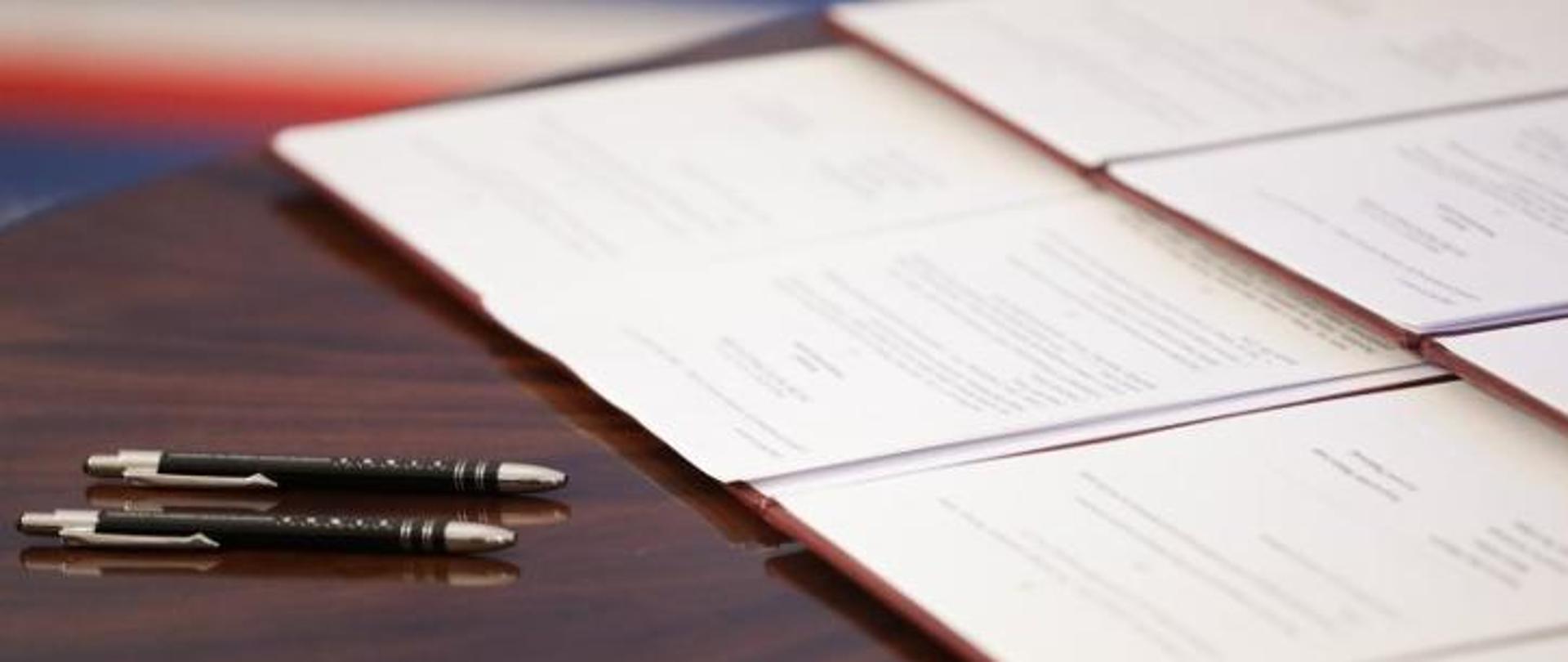 Zdjęcie przedstawia długopisy na stole oraz otwarte teczki z dokumentami, fot. Danuta Matloch 