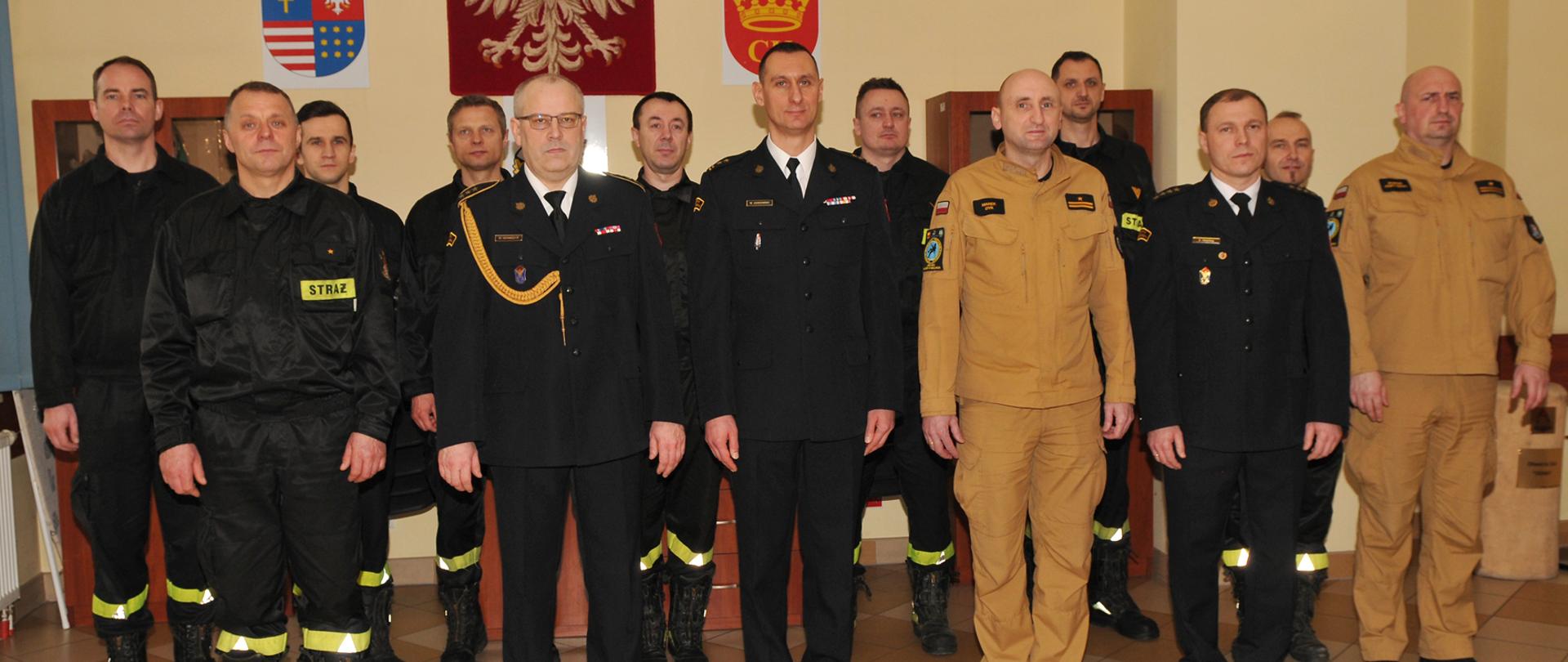 Zdjęcie przedstawia funkcjonariuszy zebranych na uroczystości pożegnania odchodzącego emeryta w sali świetlicowej Jednostki Ratowniczo-Gaśniczej Numer 3 w Kielcach.