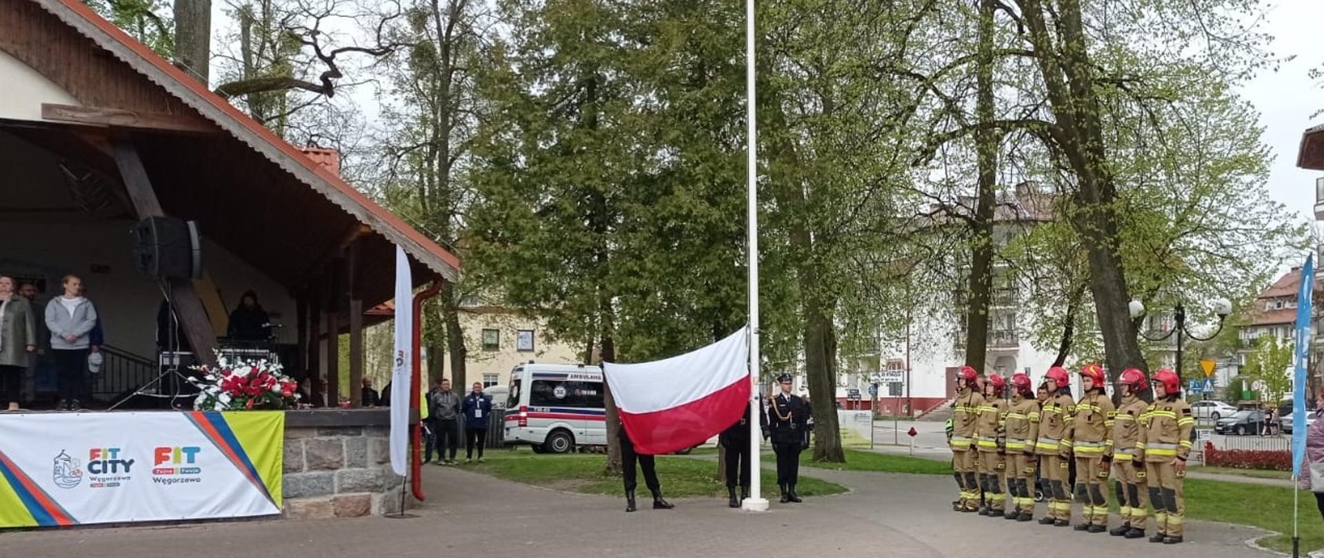 Strażacy na Placu Wolności uroczyście podnoszą flagę na maszt