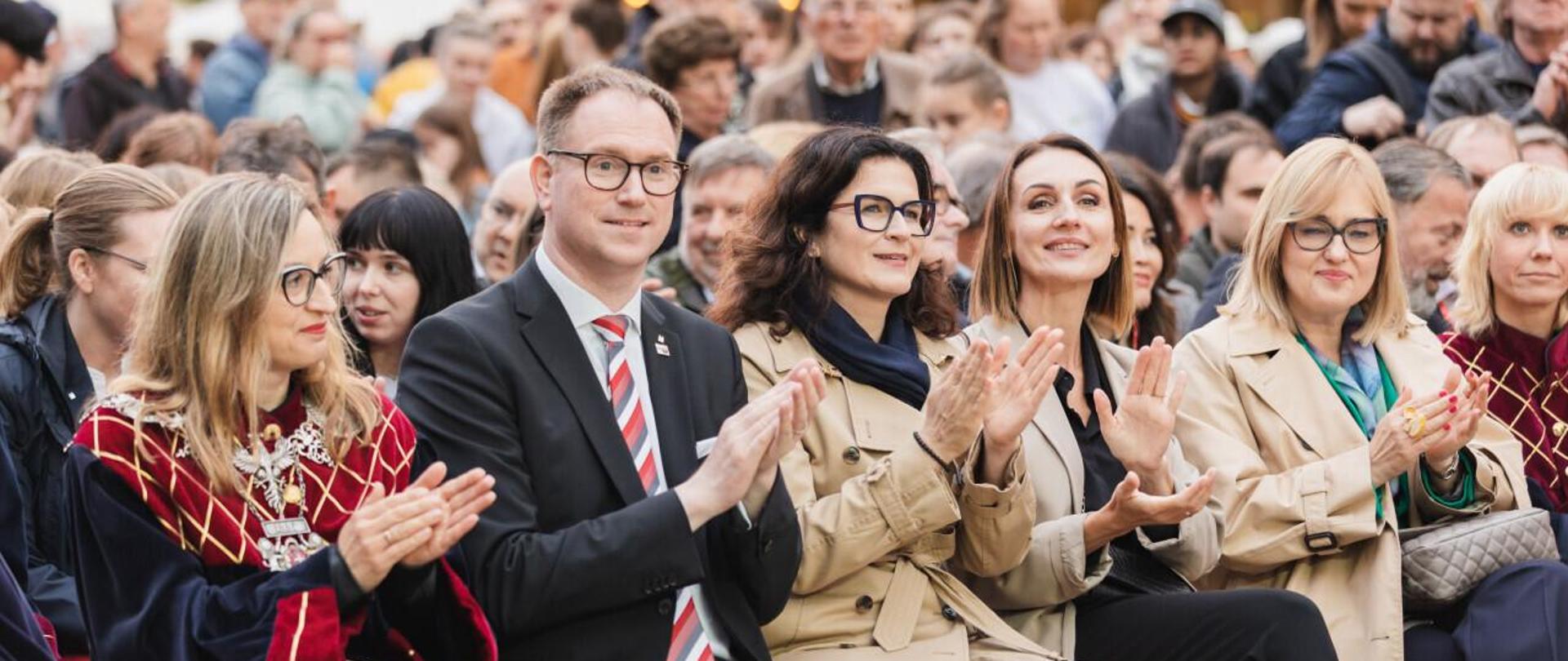 kilka osób siedzi na krzesłach ustawionych przed fontanną Neptuna