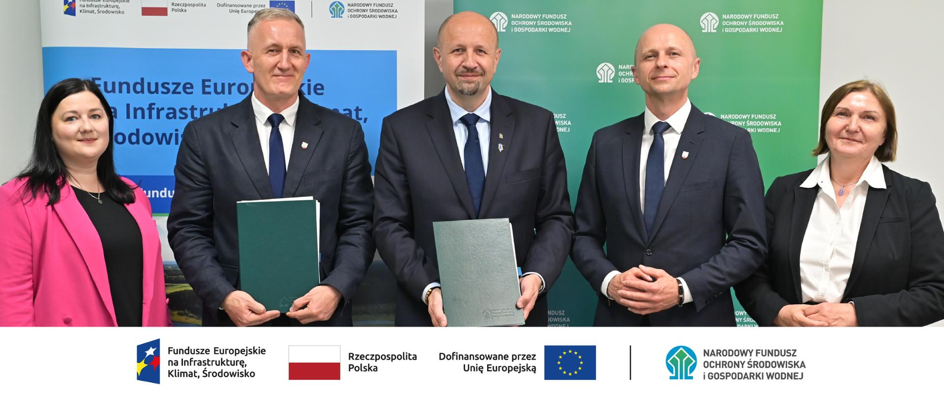 Zdjęcie grupowe. W stopce grafiki ciąg logotypów: Fundusze Europejskie na Infrastrukturę, Klimat, Środowisko, flaga Rzeczypospolita Polska, flaga UE i Dofinansowane przez UE, NFOŚiGW.