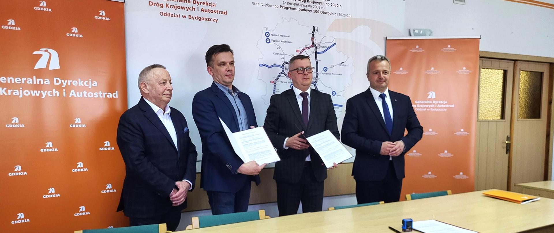 
Czterech mężczyzn w garniturach w sali konferencyjnej
