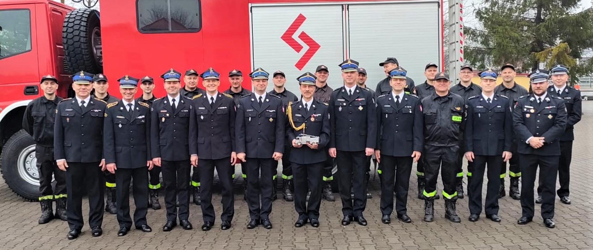 Zdjęcie grupowe, przedstawiające funkcjonariuszy biorących udział uroczystości pożegnania ze służbą mł. bryg. Arkadiusza Woronina