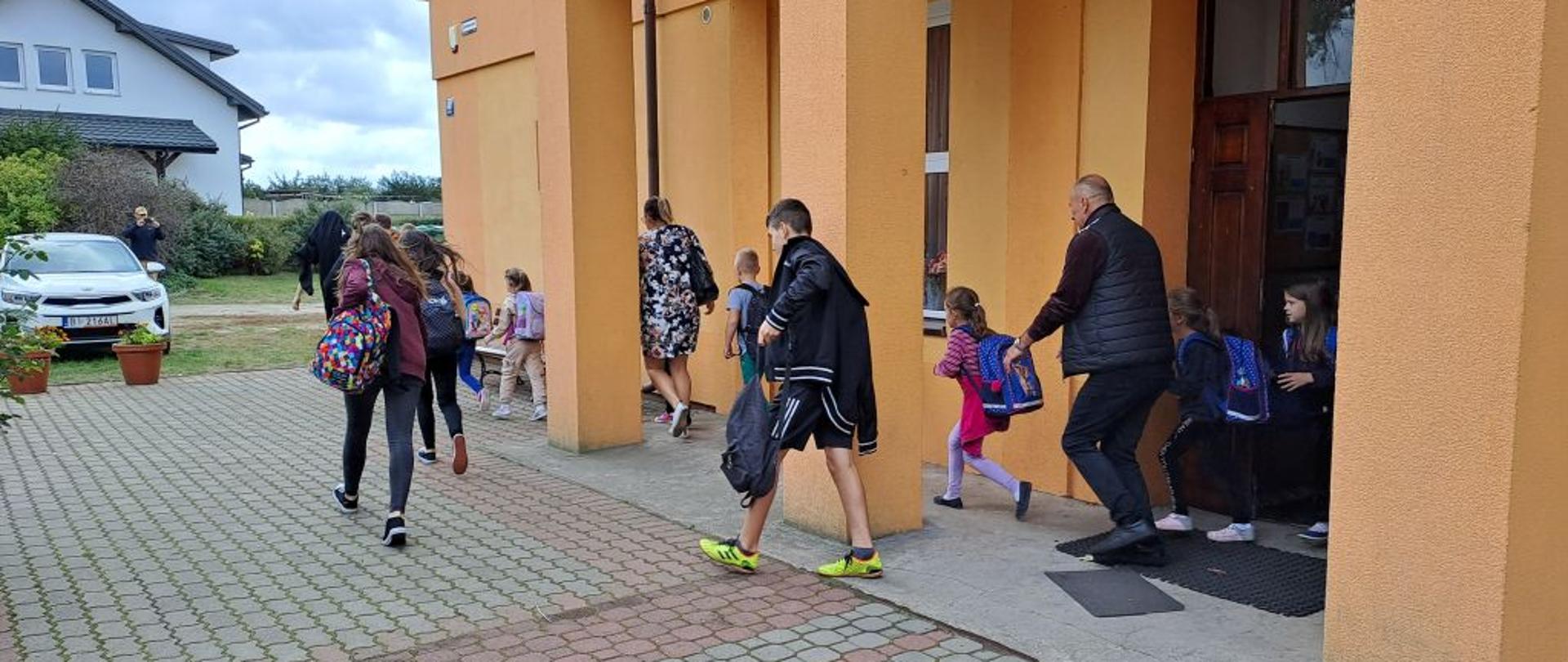 Na zdjęciu widać uczniów wychodzących z budynku szkoły.