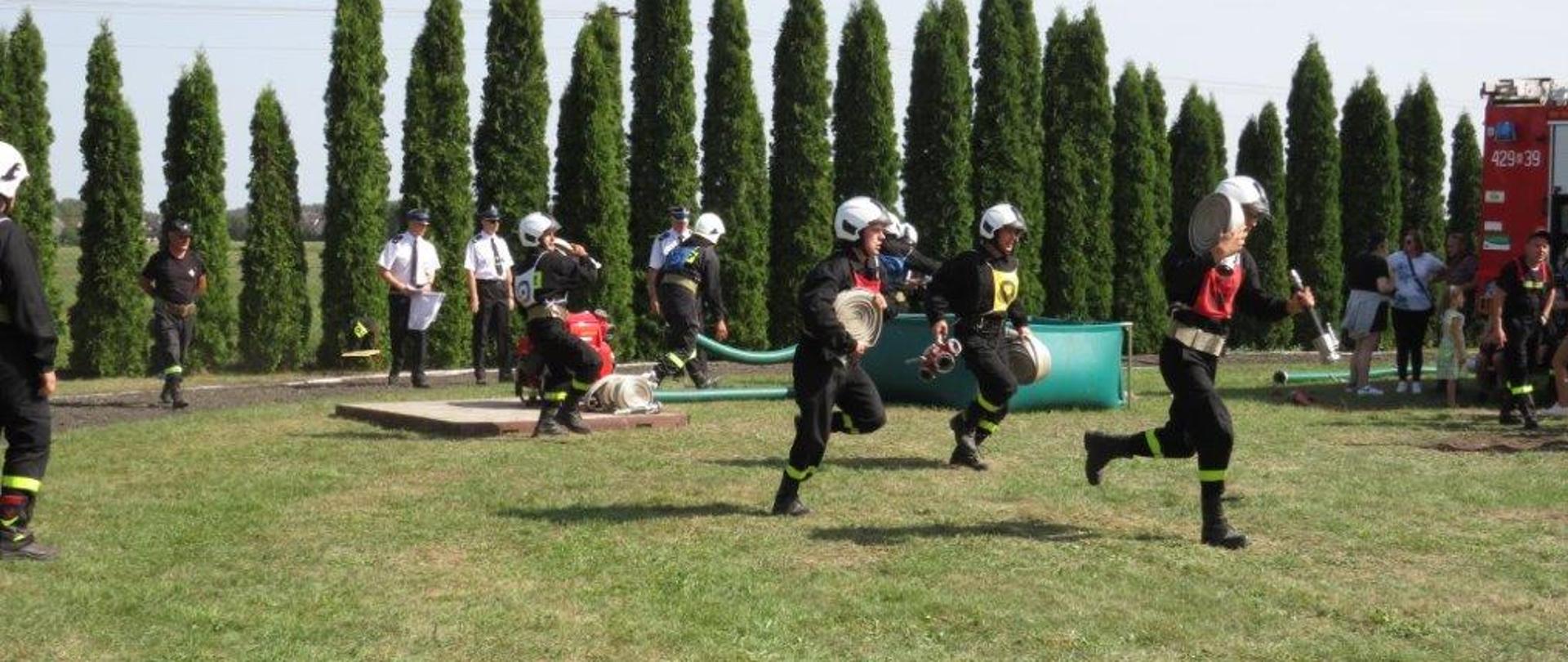 Druhowie OSP w trakcie biegu w ćwiczeniu bojowym.