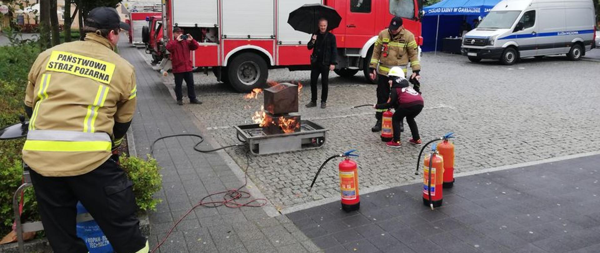 Na zdjęciu widać uczestników kampanii społecznej oraz strażaków przy stanowisku do symulacji pożaru komputera.
