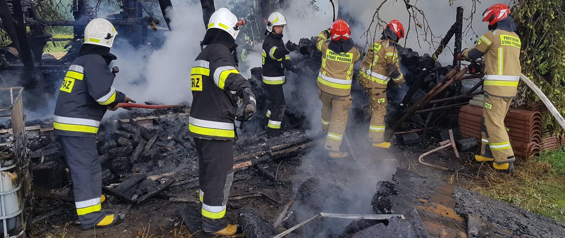 Zdjęcie przedstawia trzech strażaków OSP i trzech strażaków PSP dokonujących rozbiórki spalonej altany