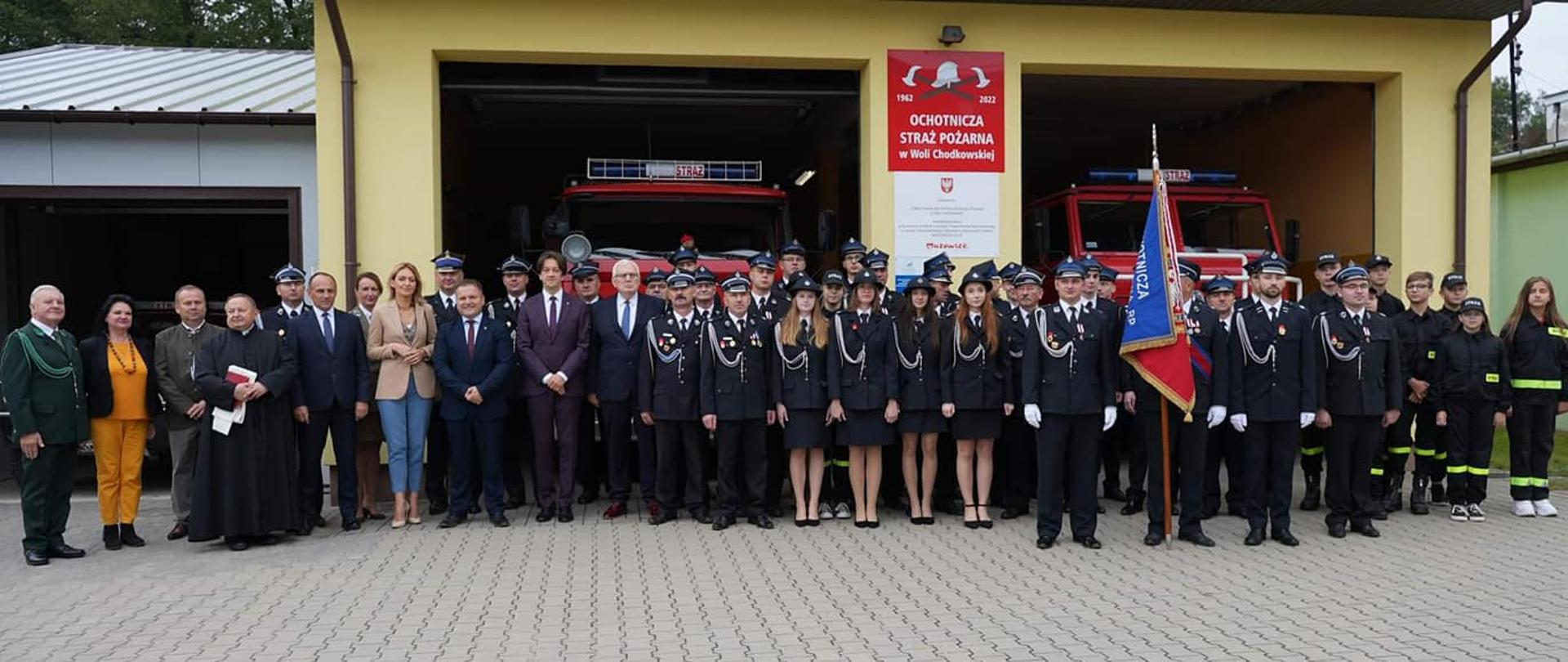 zdjęcie grupowe zrobione przed garażami remizy OSP Wola Chodkowska- zaproszeni goście druhny i druhowie 