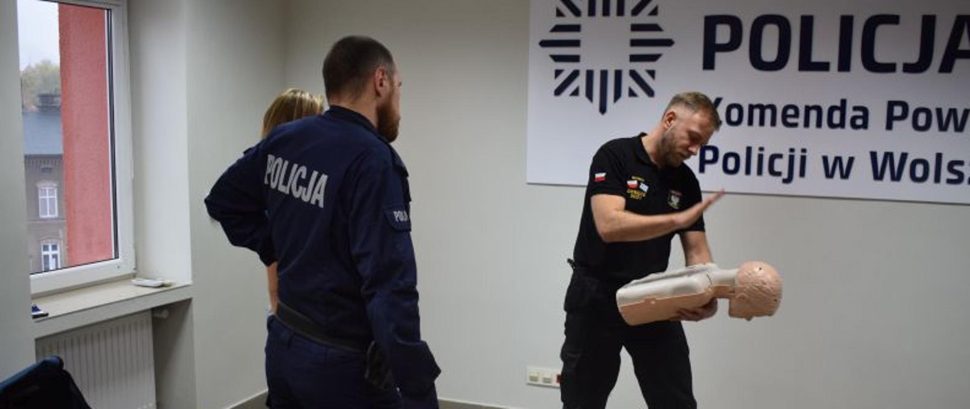 Strażak - ratownik używając fantoma pokazuje poprawny sposób uderzania w okolicę pleców podczas zadławienia.