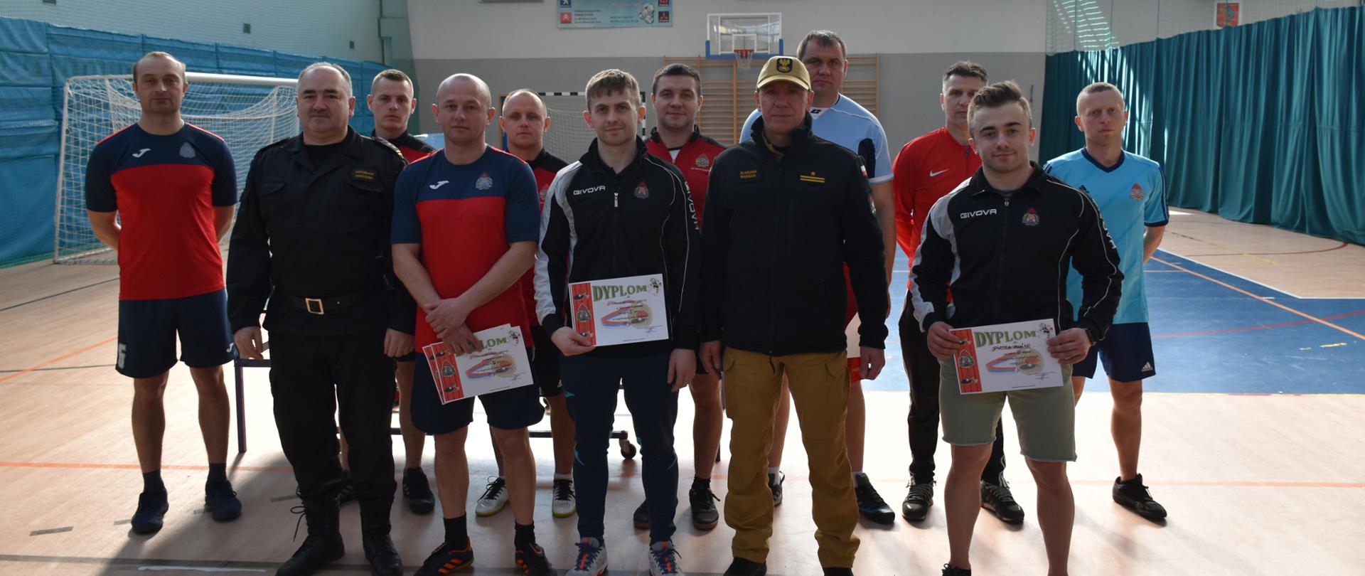 Zastępca Komendanta Powiatowego PSP Skarżysko-Kamienna wraz z dowódcą JRG Skarżysko pozują wraz z zawodnikami do zdjęcia grupowego po zakończeniu eliminacji 