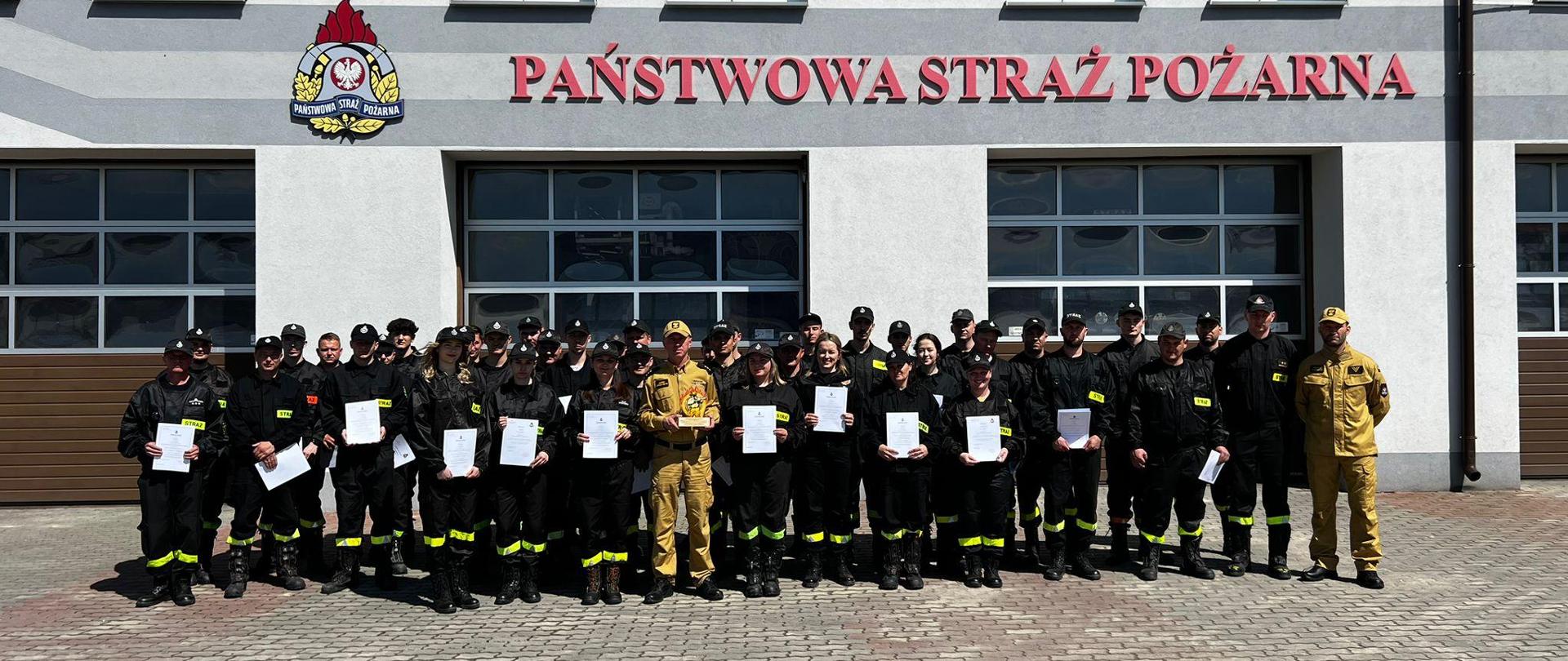 Zdjęcie przedstawia druhów i strażaków podczas zbiórki przed garażem JRG w Lubaczowie