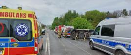 Służby ratownicze na drodze, na środku przewrócony ambulans transportowy zabezpieczony przy użyciu podpór stabilizujących.