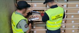 Funkcjonariusze wyjmują papierosy z kartonów z cebulą
