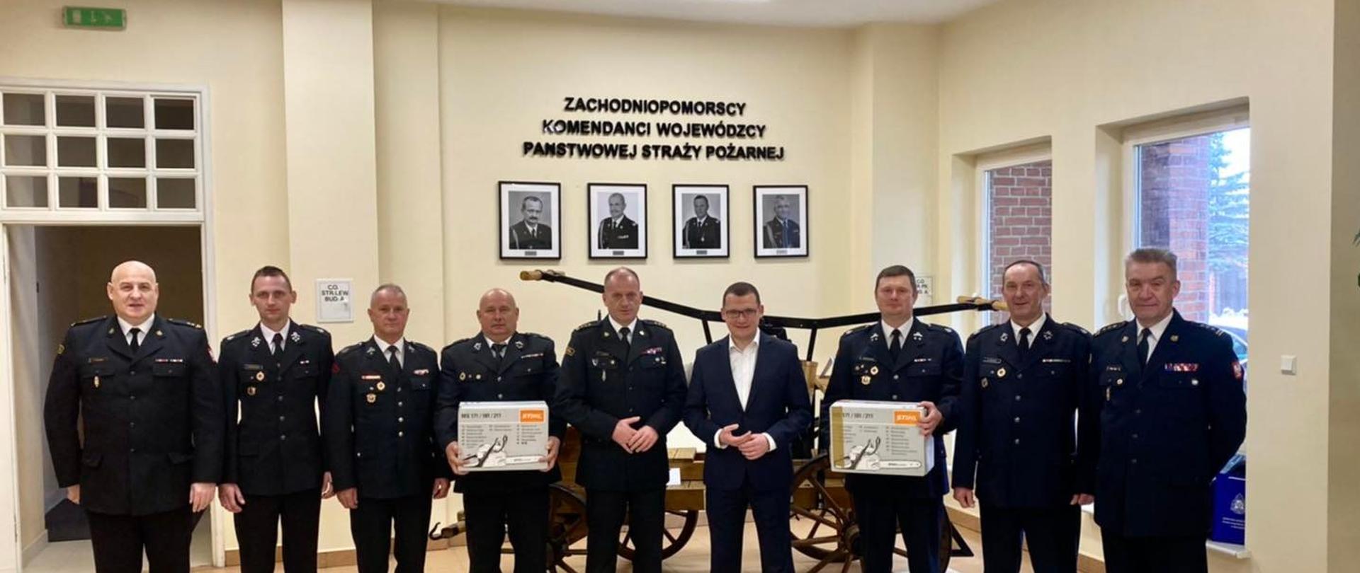 Na zdjęciu po środku wśród Druhów OSP Zachodniopomorski Komendant Wojewódzki PSP st.bryg. Jarosław Tomczyk, sekretarz stanu w MSWiA Pan Paweł Szefernaker, pierwszy od prawej Zastępca Zachodniopomorskiego Komendanta Wojewódzkiego st. bryg. Kazimierz Lesisz, po lewej Komendant Powiatowy PSP w Wałczu bryg. Dariusz Lubianiec.
W tle zabytkowy powóz z pompą oraz ściana ze zdjęciami byłych Komendantów Wojewódzkich PSP.