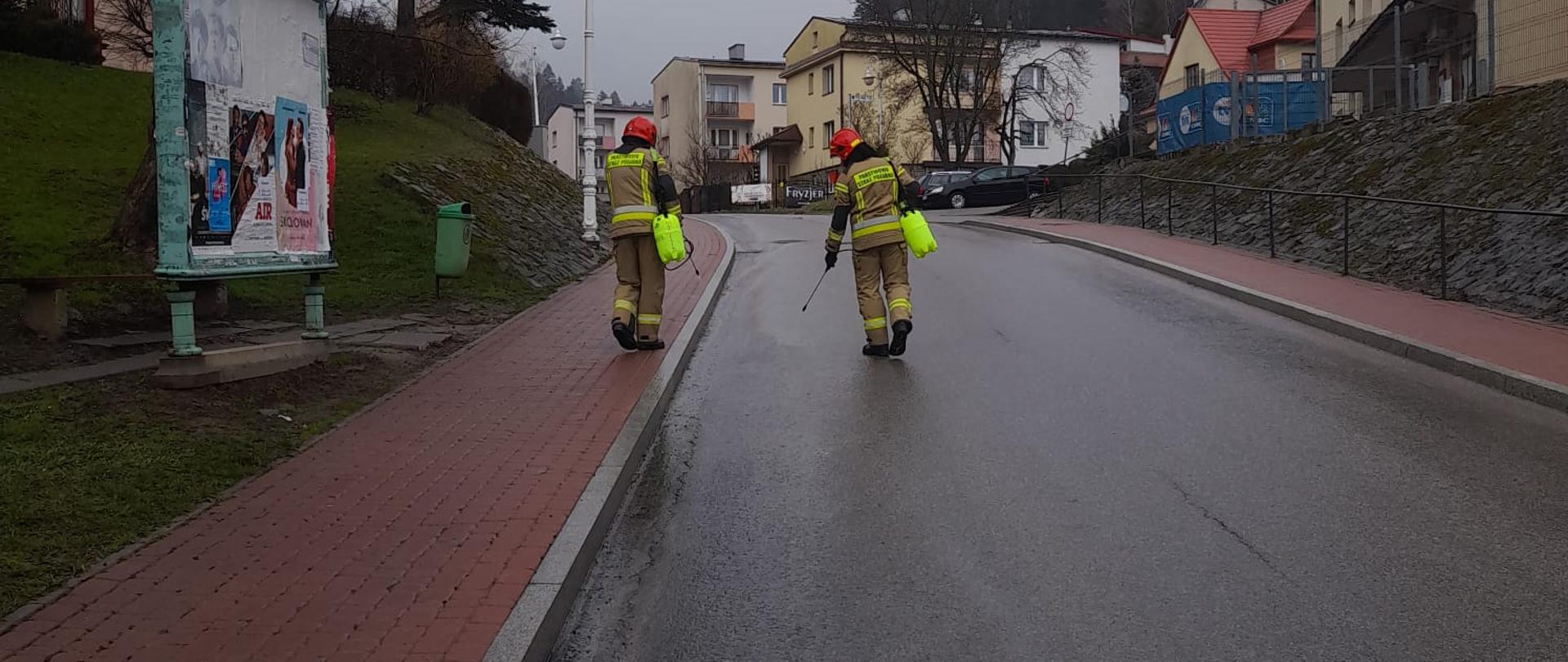 Strażacy dokonują oprysku substancji ropopochodnej na drodze