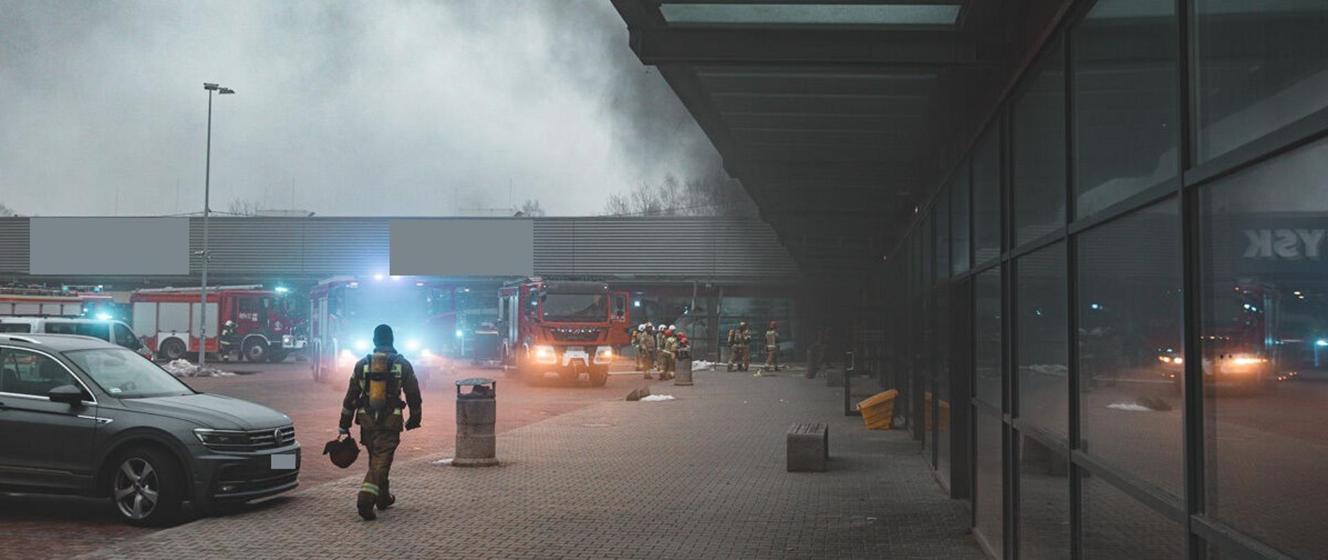 Zdjęcie strażaka i samochodów pożarniczych przy pożarze Centrum Handlowego