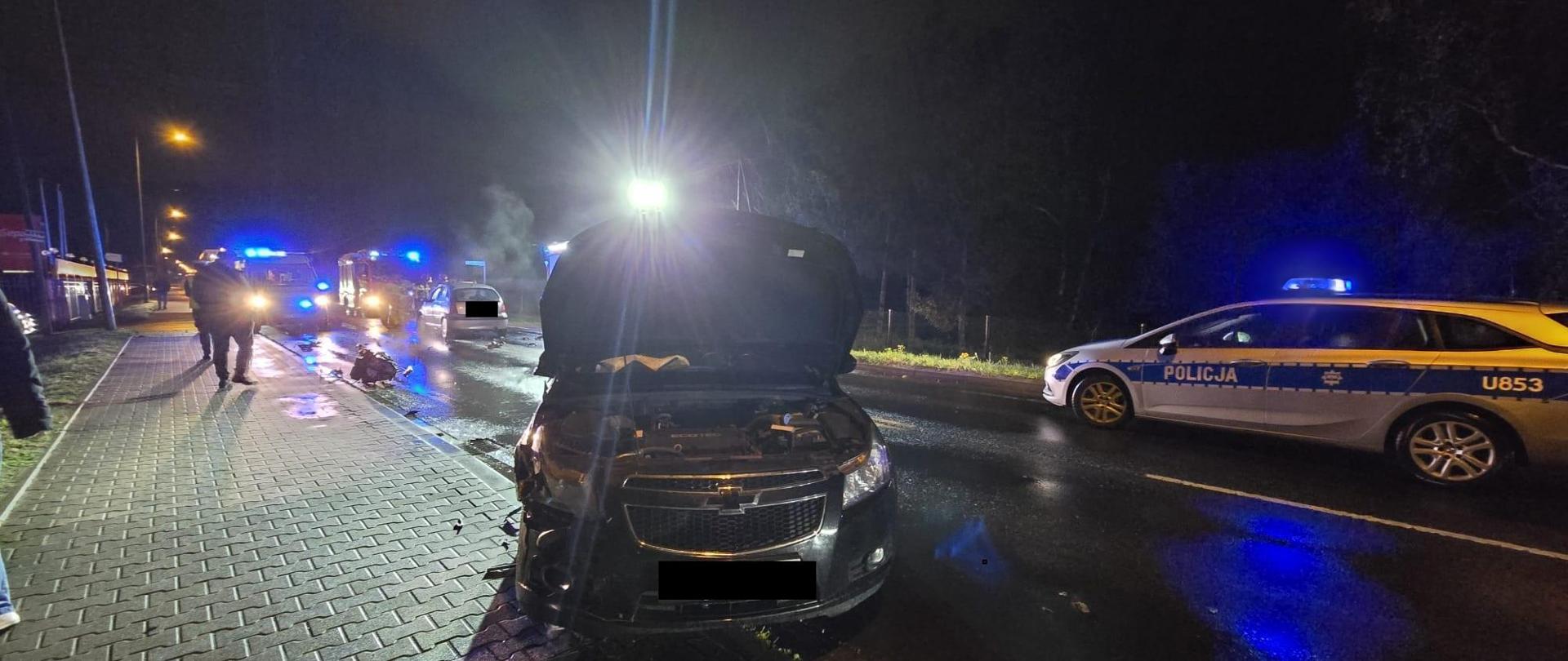 Czarny samochód z uszkodzonym przodem na drodze, jest ciemno