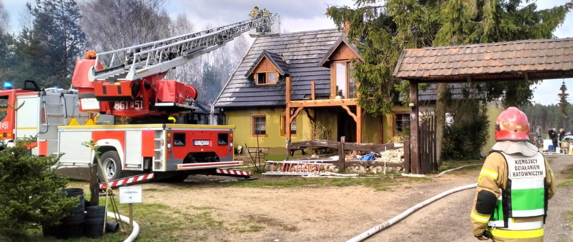 Na zdjęciu widoczny jest budynek oraz strażaki i drabina strażacka