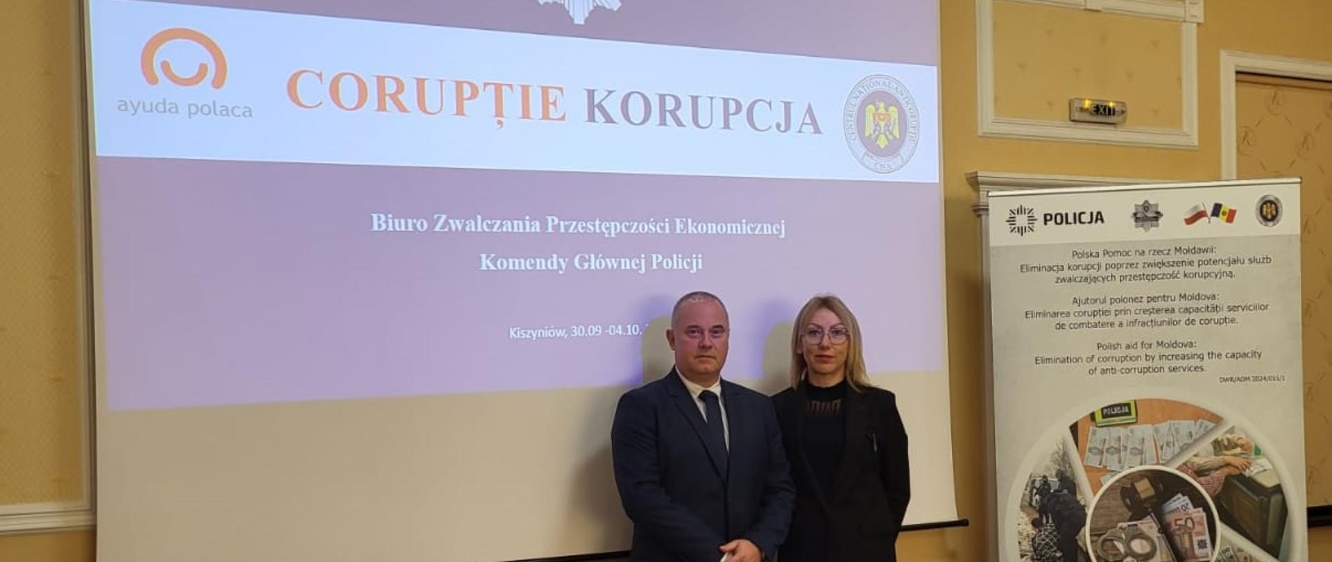 Kobieta i mężczyzna na tle ekranu z napisem Biuro Zwalczania Przestępczości Ekonomicznej Komendy Głównej Policji i logo Polska Pomoc
