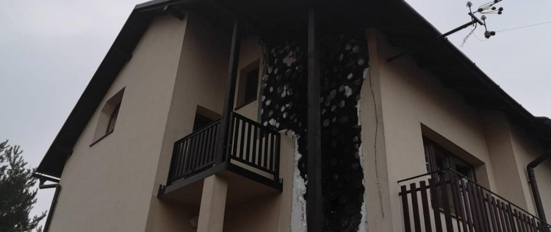 Zdjęcie przedstawia budynek mieszkalny z częściowo spaloną elewacją, czarna zwęglona ściana i widoczny styropian który nie uległ zpaleniu