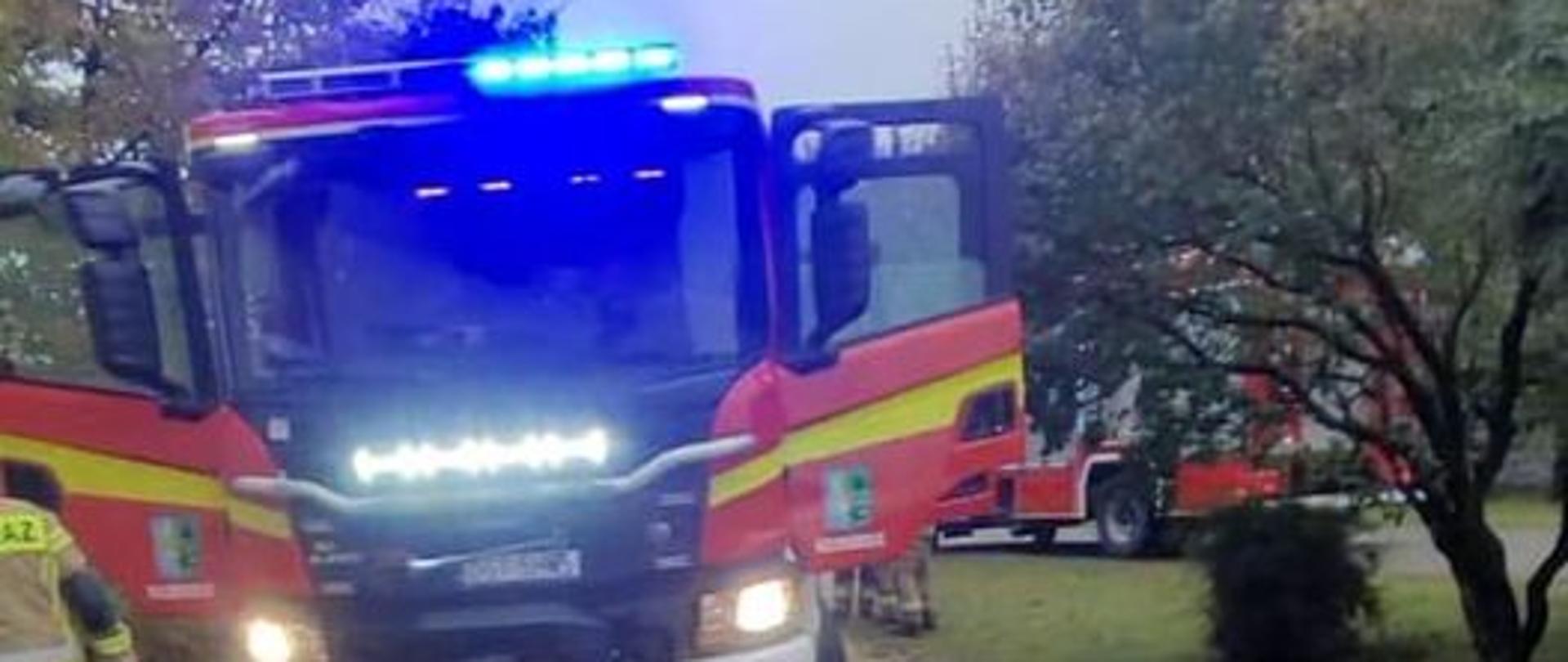 Na zdjęciu znajduje się samochód pożarniczy z włączonymi światłami wywoławczymi