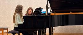 Uczestnicy warsztatów improwizacji fortepianowej podczas twórczej pracy przy fortepianie pod kierunkiem Marty Mołodyńskiej-Wheeler.