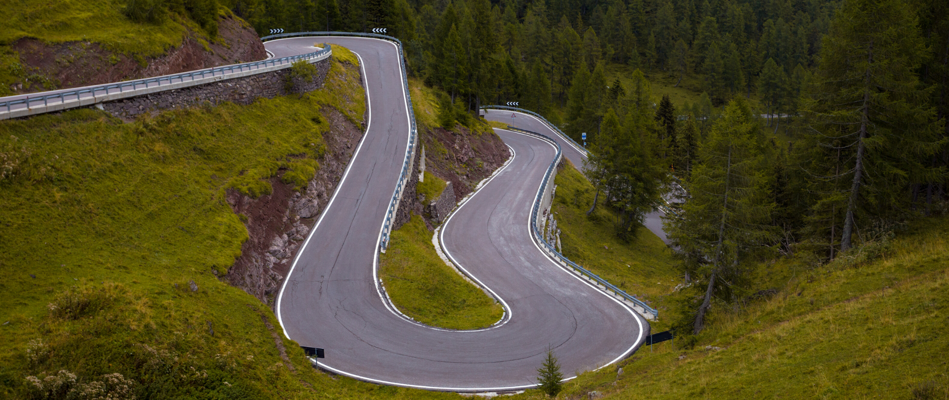 Widok na krętą, górską drogę. Wokół zielona wzgórza.