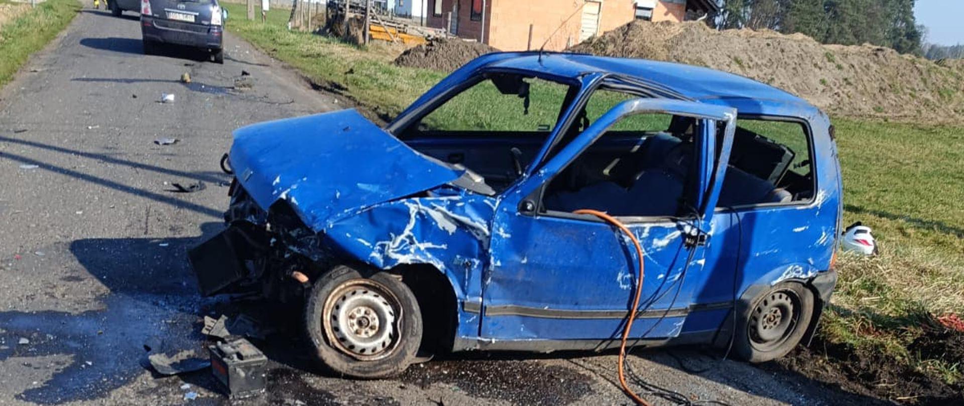 Na zdjęciu znajduje się wrak samochodu osobowego, w tle widać budynki