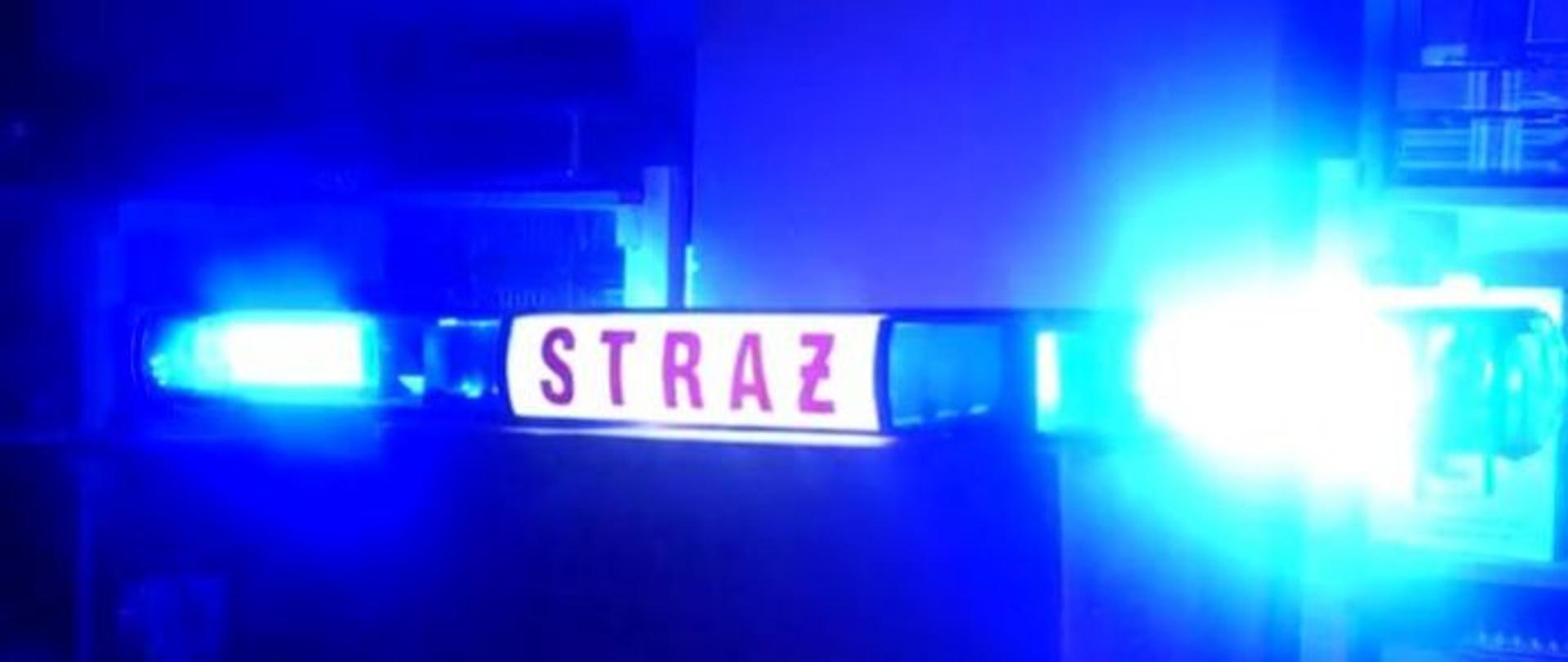 Strażacka belka z dwoma świecącymi kogutami po bokach, w środku z napisem straż