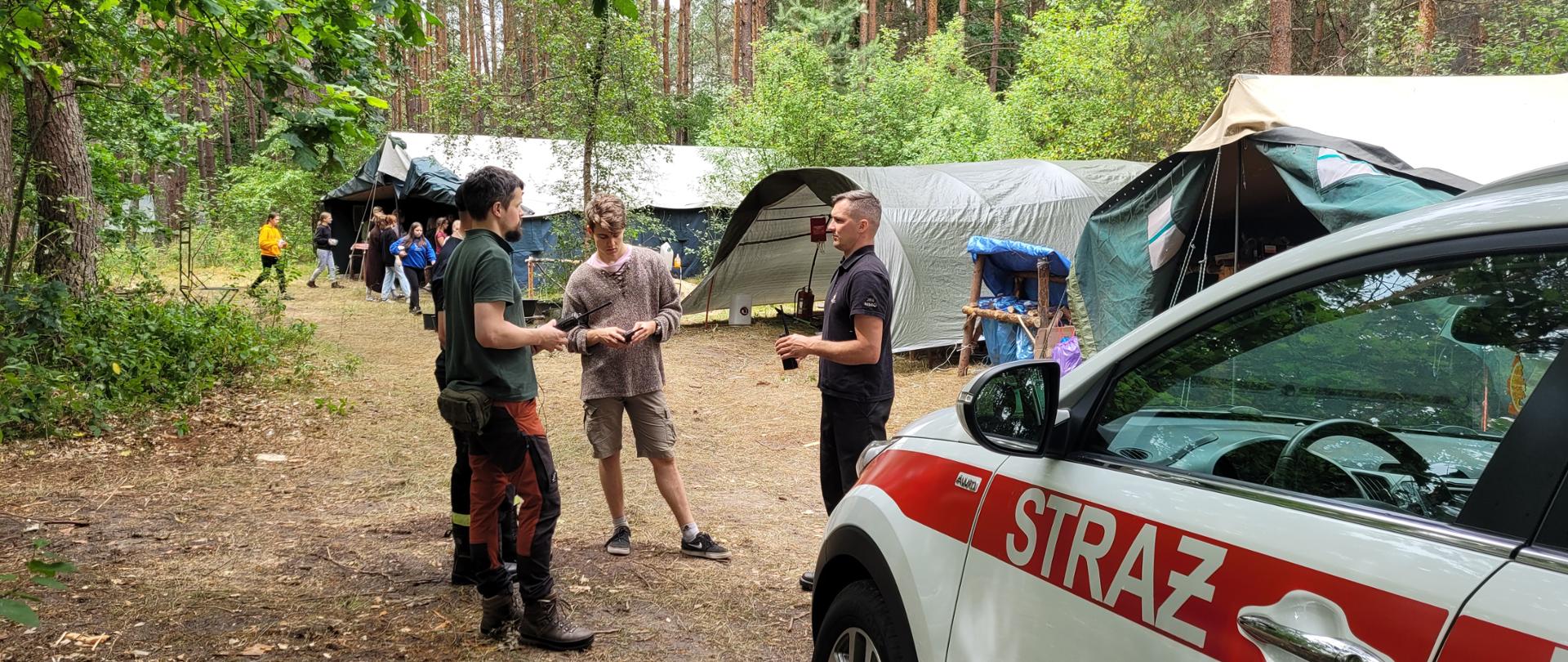 strażacy podczas wizytacji obozu harcerskiego pod namiotami