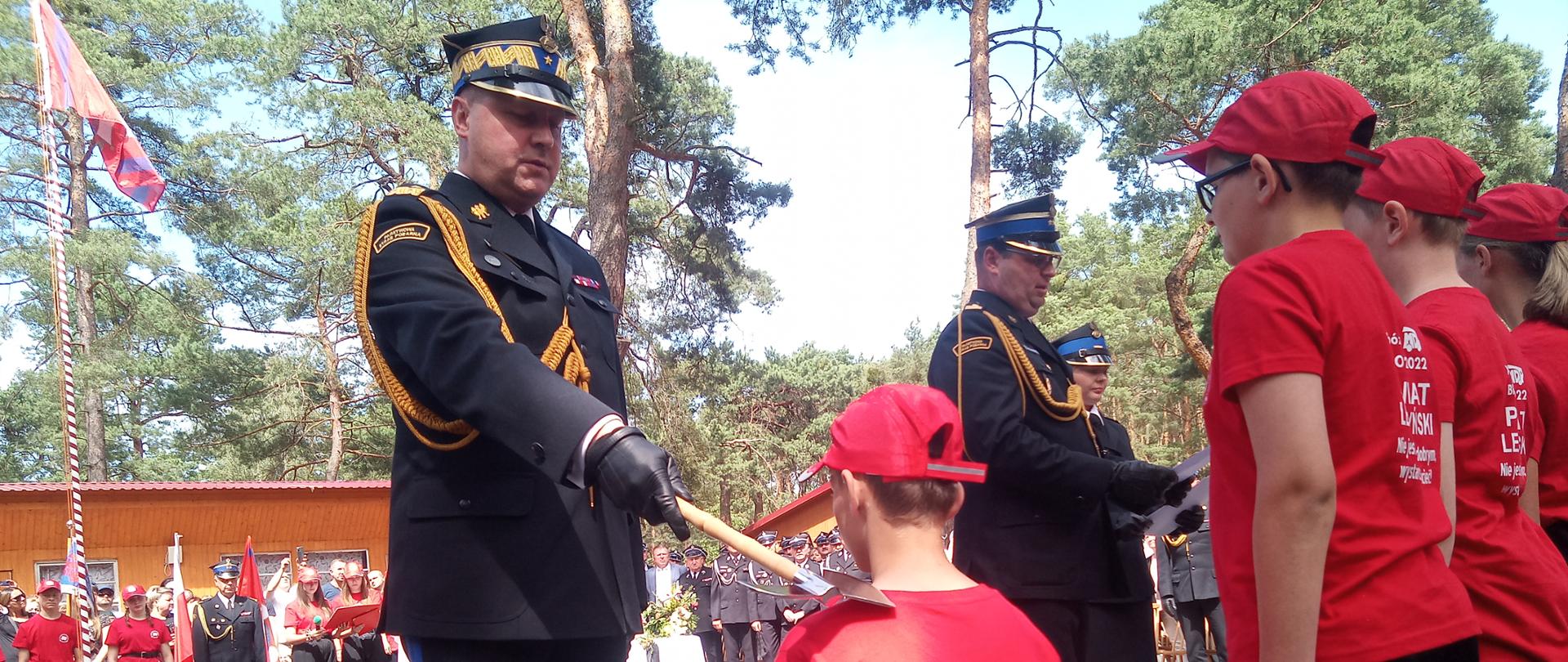 Na zdjęciu widać strażaka oraz dzieci na Obozie Szkoleniowym Młodzieżowych Drużyn Pożarniczych.