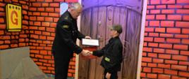 Zastępca Śląskiego Komendanta Wojewódzkiego PSP st. bryg. Rafał Świerczek wręcza nagrodę laureatowi Ogólnopolskiego Turnieju Wiedzy Pożarniczej „Młodzież Zapobiega Pożarom”