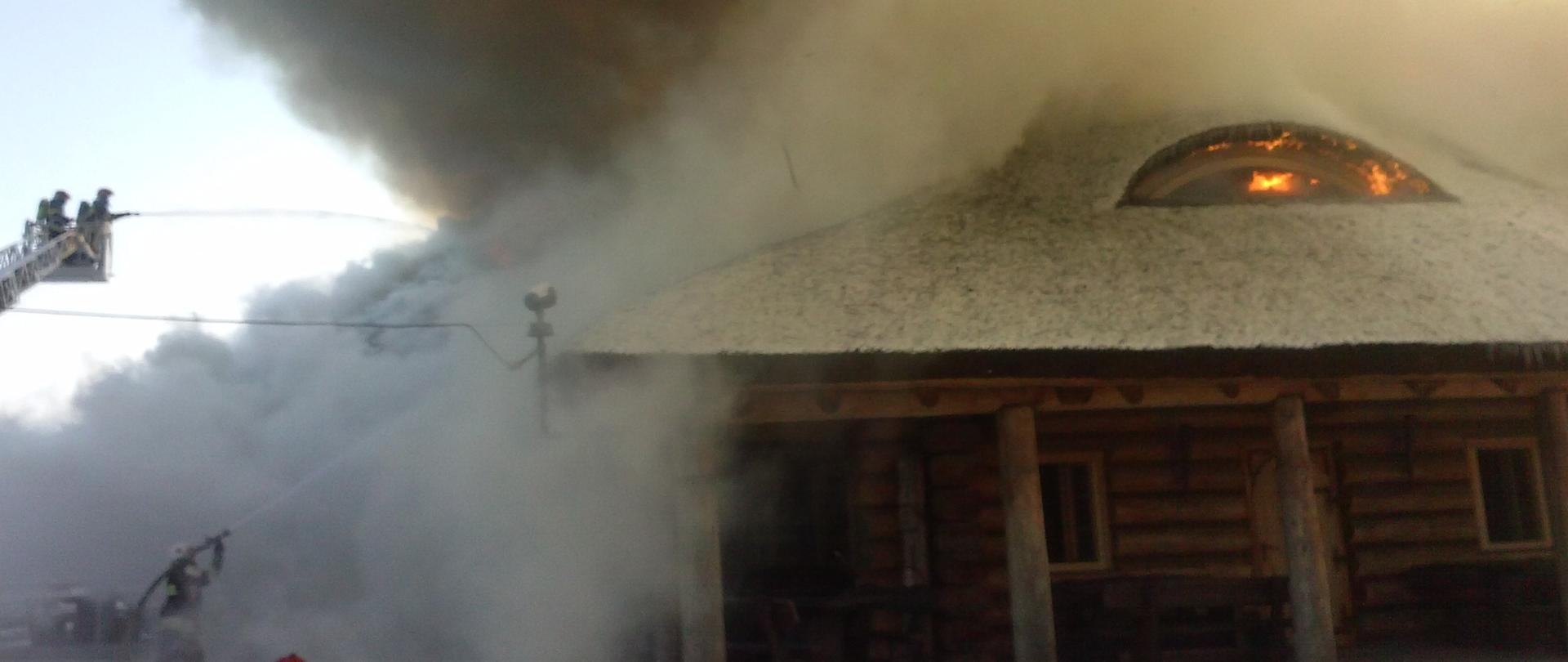 na zdjęciu widać budynek konstrukcji drewnianej objęty pożarem. Widać ogień i dużo dymu