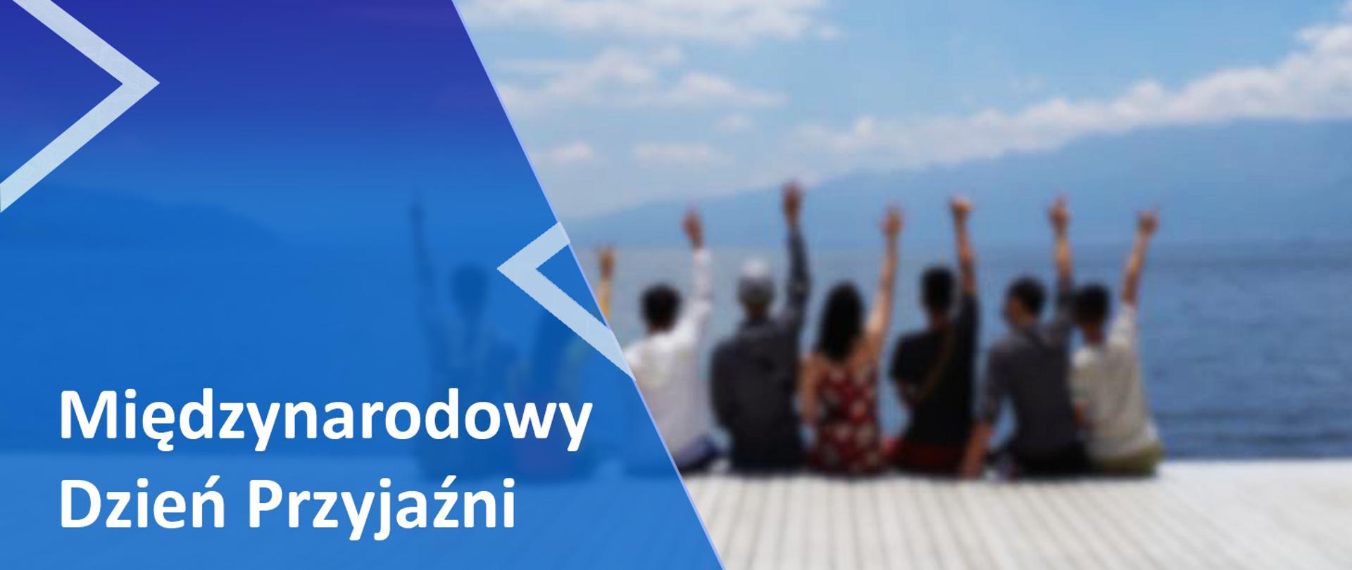 Po lewej stronie na niebieskim tle napis Międzynarodowy Dzień Przyjaźni, po prawej ludzie siedzący na pomoście
