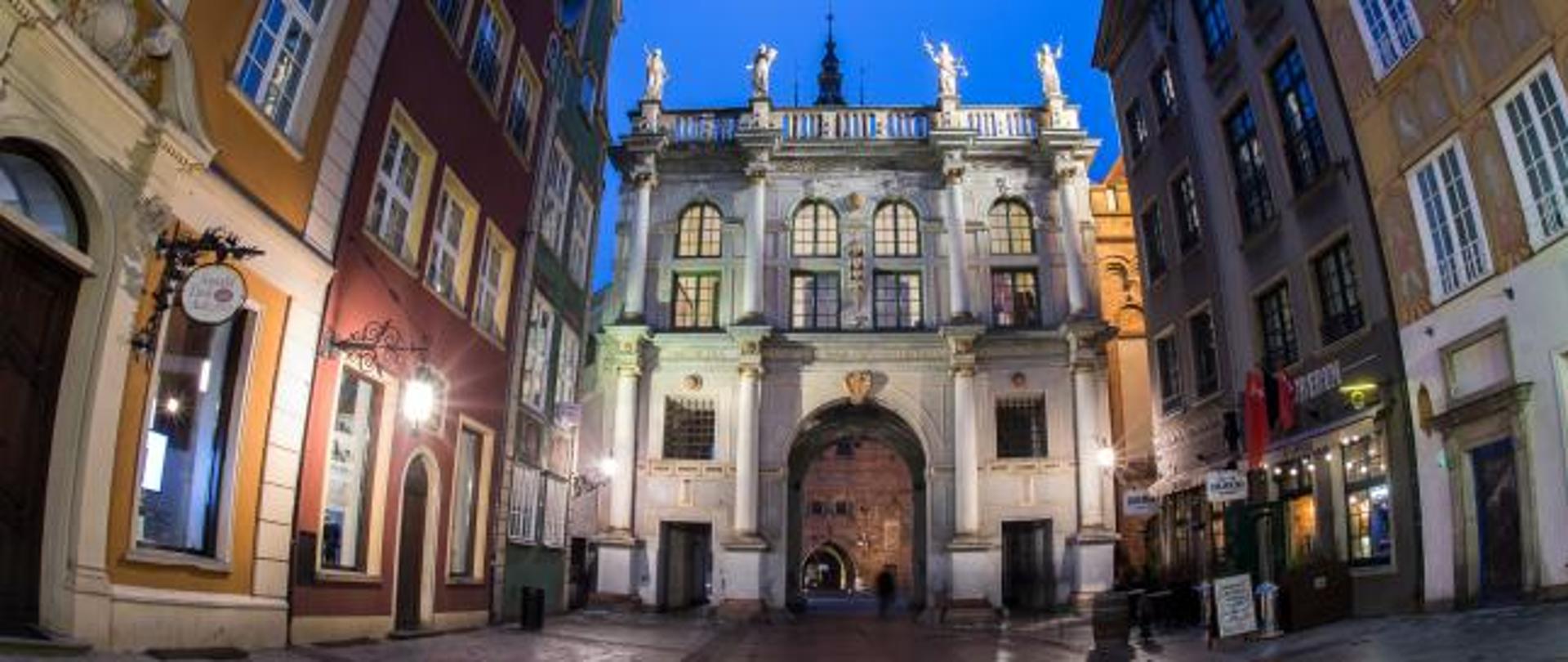 kamieniczki gdańskie nocą, na głównym planie Złota Brama