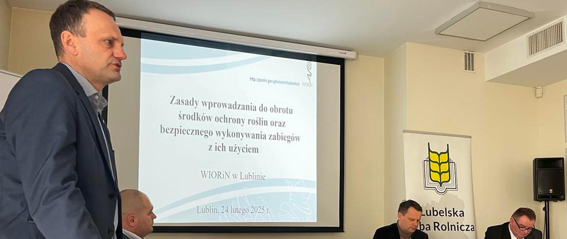 Mężczyzna przemawia na tle tablicy na posiedzeniu Delegatów Rady Powiatowej Lubelskiej Izby Rolniczej Powiatu Lubelskiego