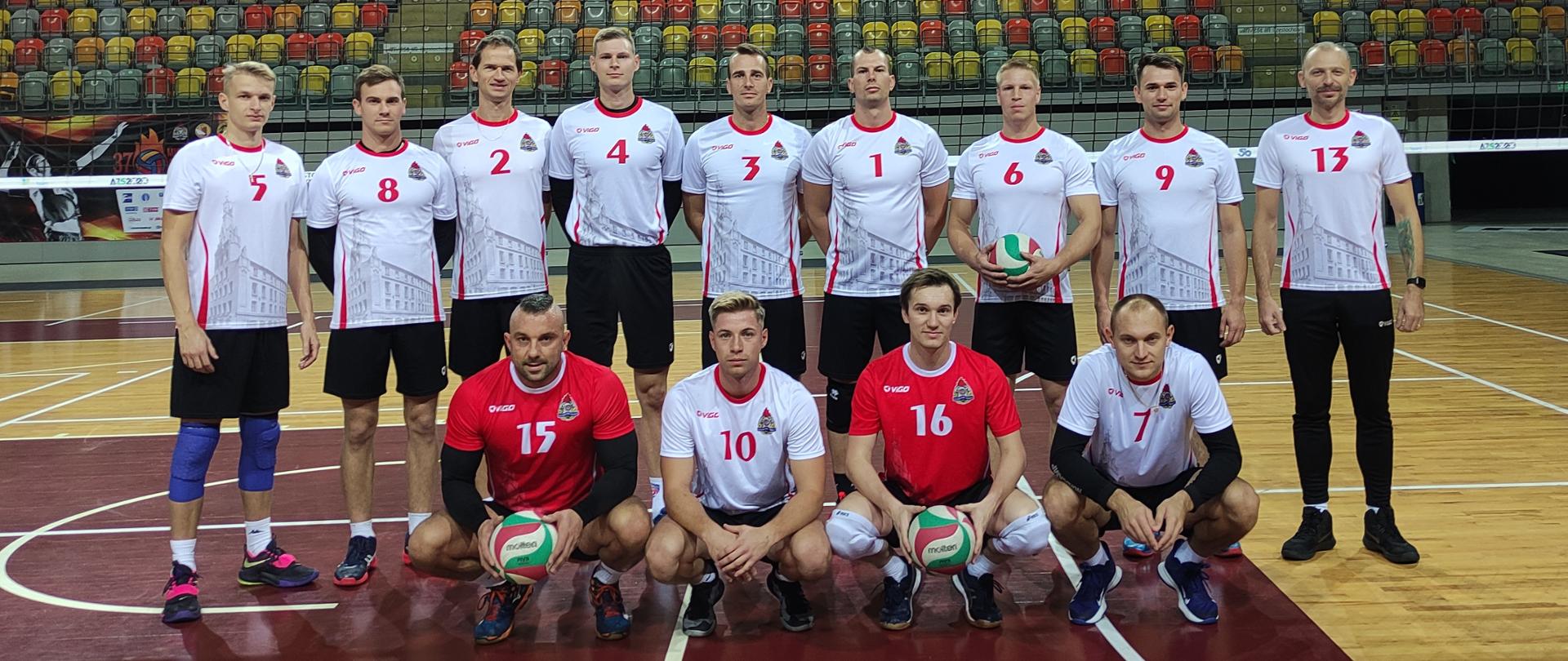 grupa sportowców siatkarzy w białytch koszulkach pozuje do zdjecia, sportowcy znajdują się na sali gimnastycznej