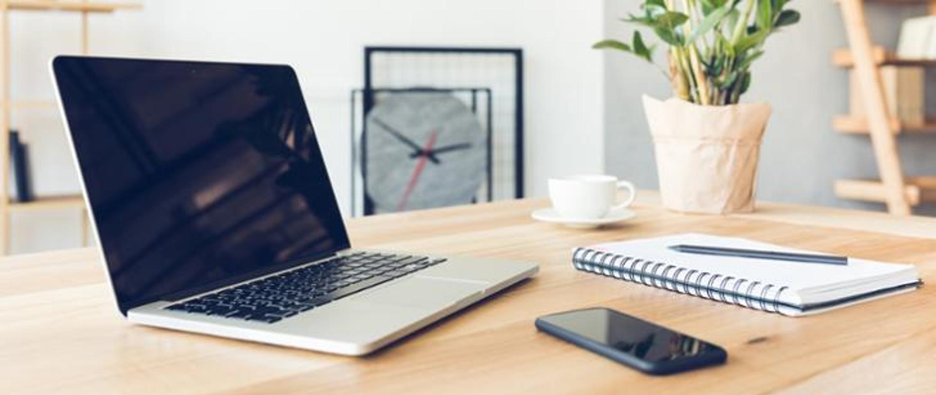 Komputer, notes i telefon na biurku.