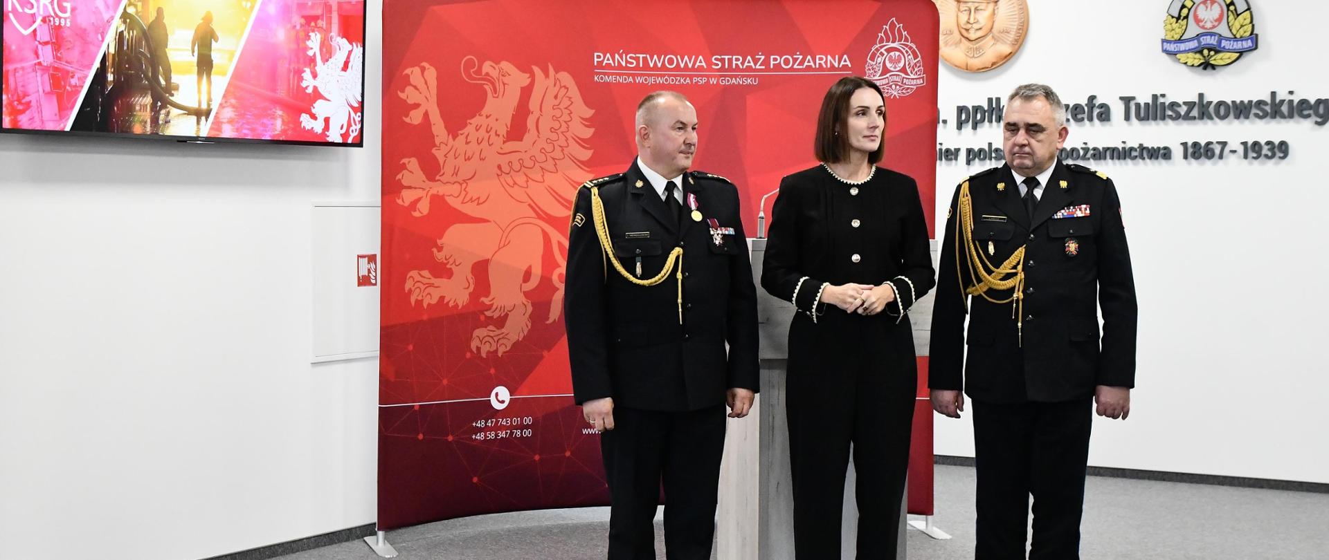 trzy osoby stoją w sali komendy wojewódzkiej PSP w Gdańsku