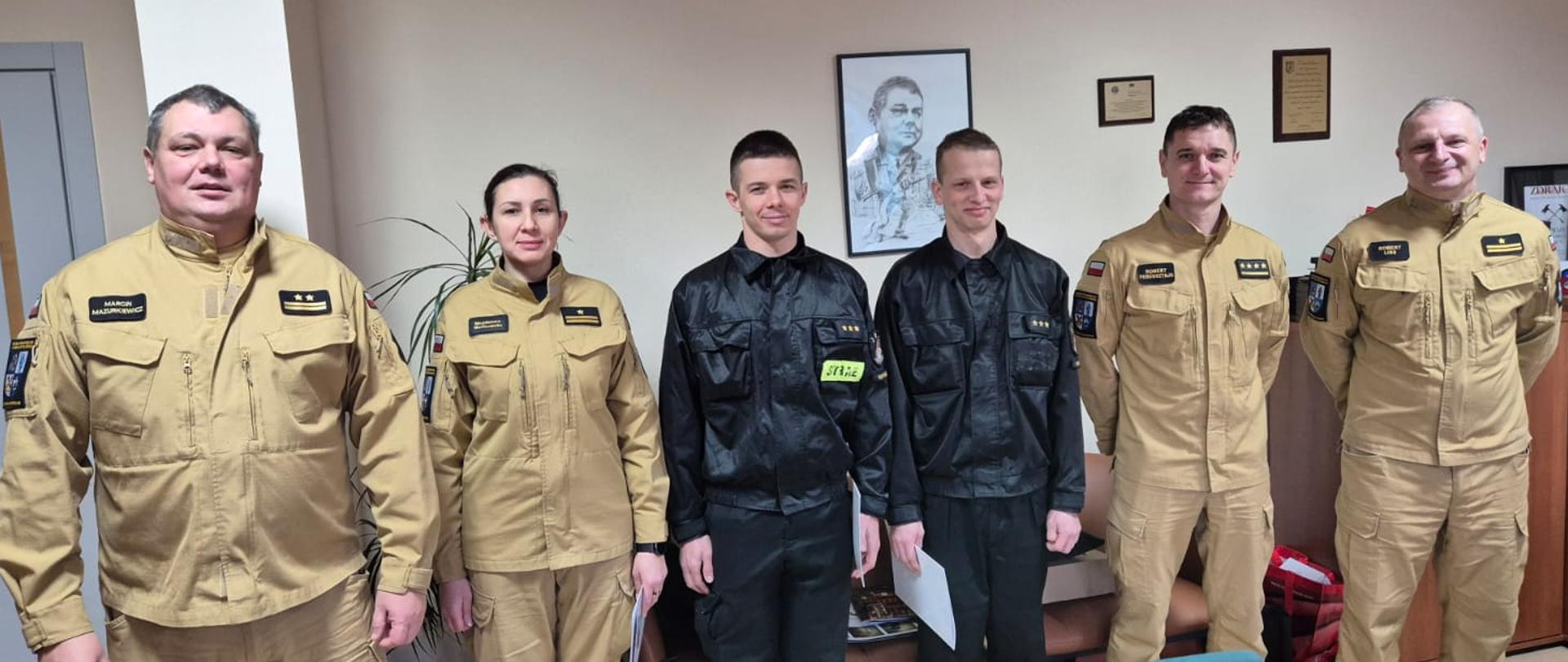 Biuro komendanta powiatowego państwowej straży pożarnej w sępólnie krajeńskim, awansowani funkcjonariusze oraz komendanci powiatowi w ubraniach służbowych pozują do wspólnego zdjęcia. 