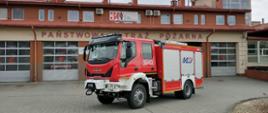 Na zdjęciu widoczny średni samochód ratowniczo gaśniczy marki Iveco, w tle widoczne bramy garażowe budynku Komendy Powiatowej PSP w Strzyżowie.