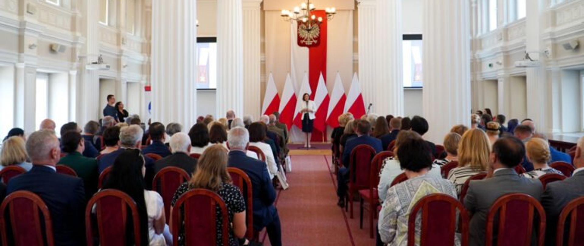 Wojewoda podkarpacki Ewa Leniart przemawia w sali kolumnowej podczas uroczystości wręczenia odznaczeń państwowych dla pracowników inspekcji sanitarnej. Wokół zgromadzeni uczestnicy uroczystości